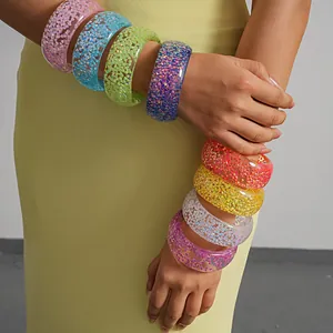 Close-up of colorful iridescent resin bangles stacked on a model's arm for summer jewelry.
