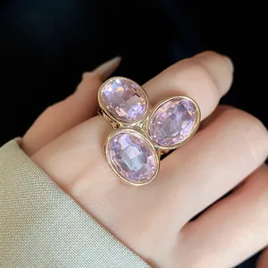 Detail shot of a vintage gold open ring with three oval pink crystals on a finger.