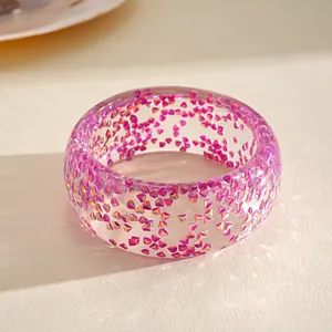 Detail of a transparent resin bangle featuring pink geometric glitter fragments
