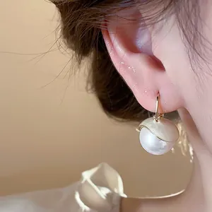 Close-up of French elegant pearl drop earring with gold enamel cap shown on ear lobe