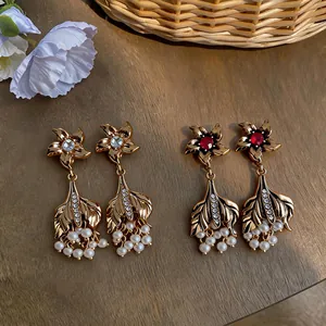 Detailed close-up of vintage gold fish tail earrings with pearls and crystals on wood