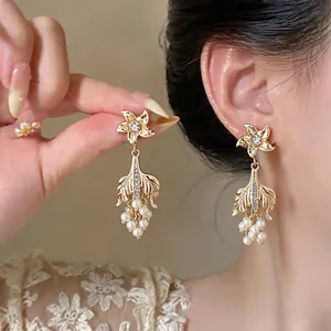 Detailed close-up view of elegant vintage gold fishtail earrings with pearls and crystals.