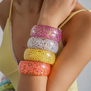 Macro detail of colorful iridescent resin bangles on a female arm in dopamine fashion style