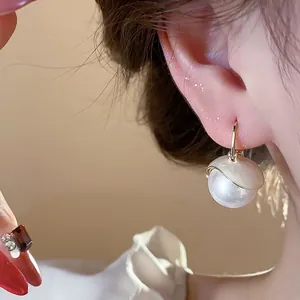 Close-up detail of elegant French style pearl drop earrings with golden design