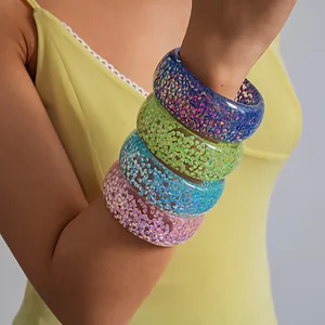 Close-up of four colorful chunky resin bangles featuring iridescent glitter textures