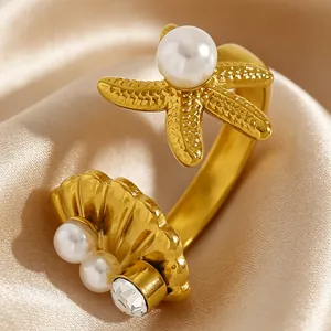 Détail d'une bague étoile de mer et coquillage en acier doré avec perles blanches et zircon
