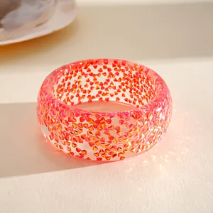 Detailed macro shot of an iridescent resin bangle with colorful geometric glitter.