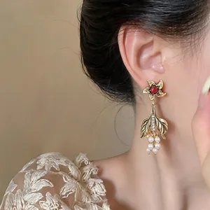 Detailed view of vintage palace style gold earrings with pearls and red gemstone