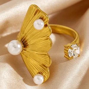 Gros plan d'une bague dorée en acier inoxydable avec motif coquillage, perles et un zircon