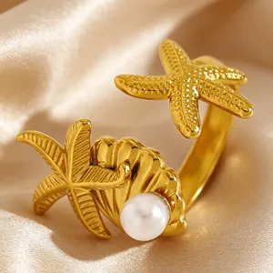 Gros plan d'une bague étoile de mer et coquillage en acier doré avec perle blanche