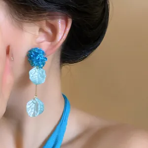 Close-up detail of stylish blue hydrangea petal tassel earring worn on a female model's ear