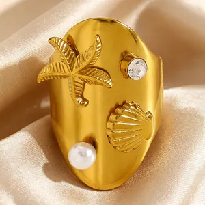 Vue détaillée d'une bague en acier doré avec étoile de mer, coquillage, perle et zircon