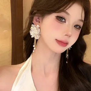 Close-up view of elegant French style white flower tassel earrings worn by a model