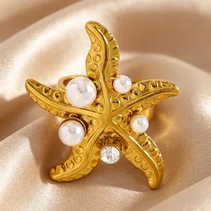 Gros plan d'une bague étoile de mer dorée avec des perles blanches et un zircon scintillant.