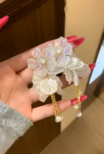 Detailed view of French style earrings with pearlescent flowers and gold chain tassels