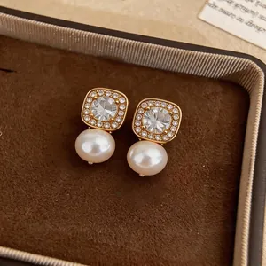 Elegant gold pearl stud earrings featuring a square zirconia halo for a luxury look