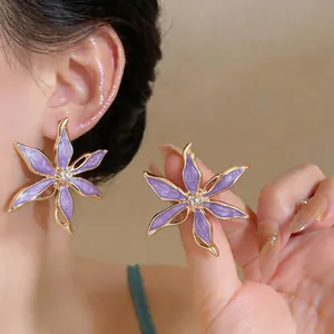 Dettaglio di orecchini a fiore viola eleganti con centri impreziositi da cristalli