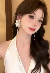 Close-up view of elegant French style white floral tassel earrings worn by an Asian model