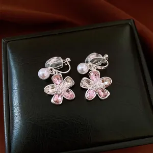 Elegant pink crystal flower clip-on earrings with pearls displayed on a black leather box