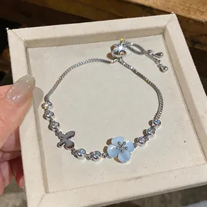 Close-up of elegant silver bracelet with cat-eye flower and zircon butterfly charms.