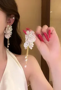 Detailed view showing the intricate white floral design and gold tassel of these earrings