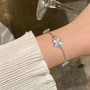 Detailed view of a silver bracelet with zircon and cat's eye stone flower charms on a wrist