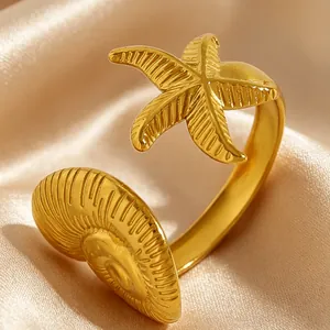 Vue détaillée d'une bague en acier inoxydable avec étoile de mer et coquillage dorés