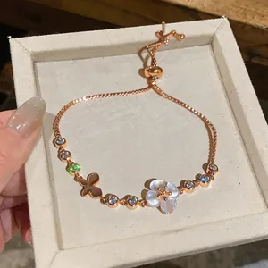 Detail of rose gold bracelet featuring zircon butterfly and white shell flower charms