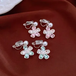 Detail view of crystal flower clip-on earrings with elegant white pearls and silver finish.