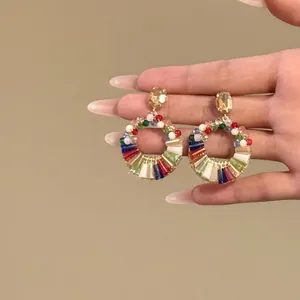 Dettaglio ravvicinato di orecchini circolari in cristallo colorato con eleganti borchie.
