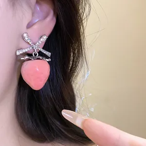 Detail shot of sweet pink strawberry earrings with sparkling zircon bow detail.