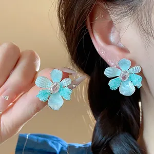 Macro view of light blue flower stud earrings with zircon and glass details