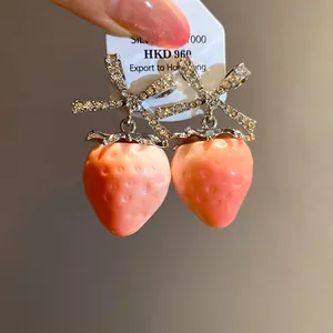 Sparkling crystal bow stud earrings with a sweet pink strawberry drop detail