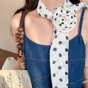 Close-up of vintage polka dot chiffon scarf with large decorative flower detail.