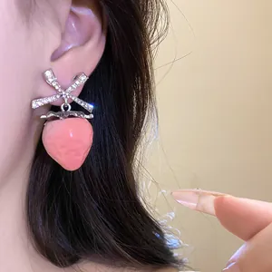 Detailed view of a sweet pink strawberry drop earring with a sparkling rhinestone bow
