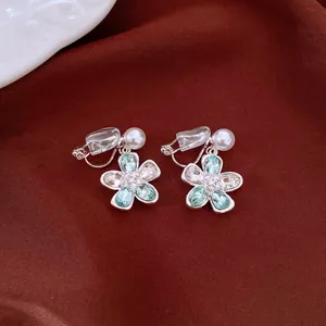 Detail view of flower-shaped clip-on earrings with green rhinestones and pearls