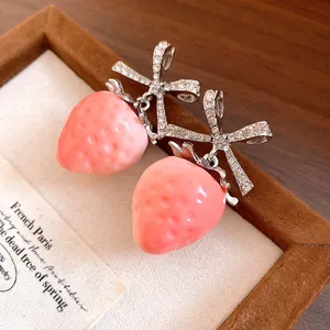 Close-up of sweet pink strawberry earrings with sparkling zircon-encrusted bows.