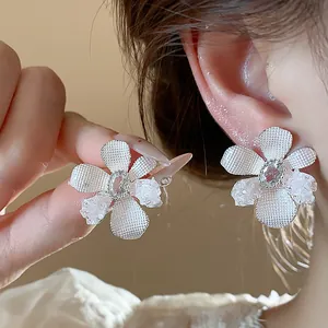 Close-up of floral stud earrings featuring textured petals and a sparkling zircon center.