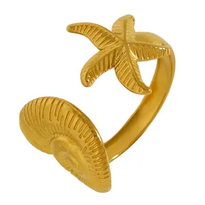 Gros plan des motifs étoile de mer et coquillage dorés sur une bague ouverte réglable.