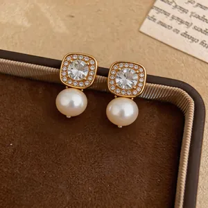 Close-up of elegant gold-tone pearl earrings with sparkling cubic zirconia stone settings