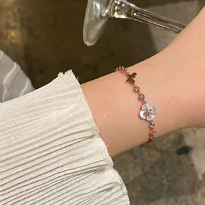 Detailed close-up of rose gold bracelet with cat-eye flower and butterfly charms on wrist