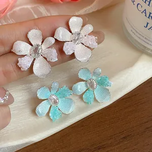 Close-up of delicate zircon and glass flower stud earrings with intricate textured petals.