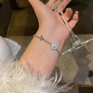 Close-up detail of silver bracelet with zircon butterfly and flower charms on wrist.