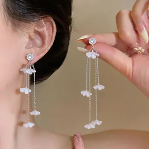 Nahaufnahme langer Gänseblümchen-Quastenohrringe mit weißen Blüten und glitzernden Steckern