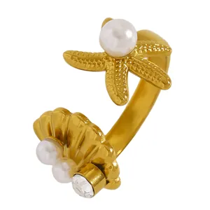 Détail d'une bague ouverte étoile de mer et coquillage dorée avec perles et petit zircon.