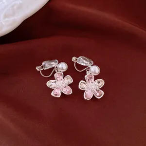 Close-up of elegant pink crystal flower ear clips with white pearl accents and soft pads
