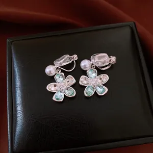Close-up of elegant flower clip-on earrings with crystals and pearls on a black gift box