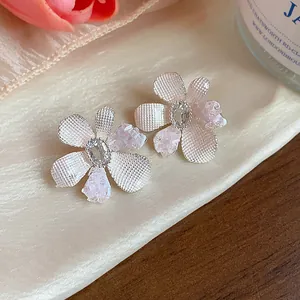 Exquisite flower stud earrings with pink zircon crystals on a soft satin background.