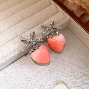 Close-up of sweet strawberry drop earrings with sparkling zirconia bows in a jewelry tray.