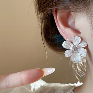 Detail showing the intricate mesh and glass petal textures of the flower stud earring.